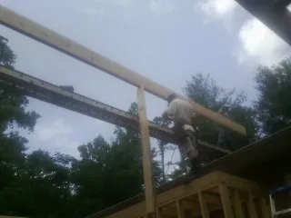Carpenter setting a ridge beam over a new addition frame — Ice Dam Removal by Roofing Brothers in Bedford